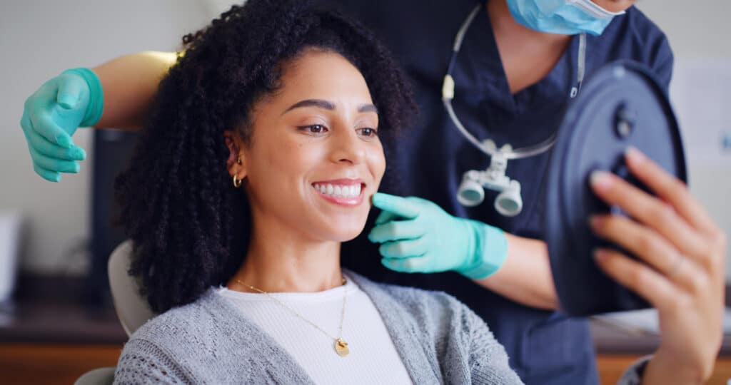 Female sitting in the dental chair looking at her smile in a mirror