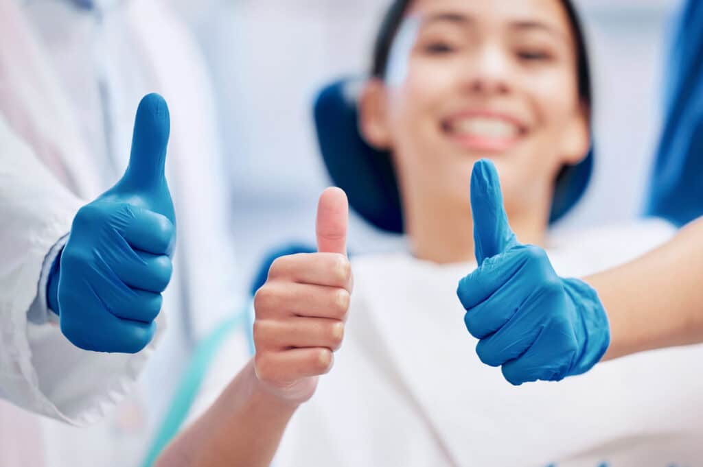 Patient and dentist giving a thumbs up showing trust